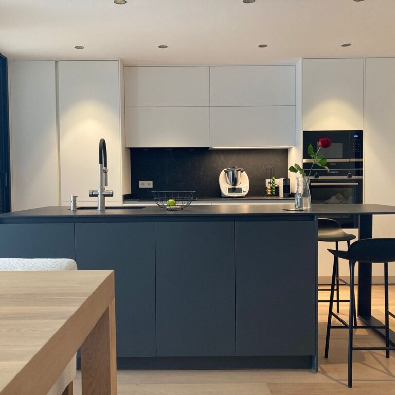 Cocina moderna en blanco y gris con isla central y electrodomésticos integrados.