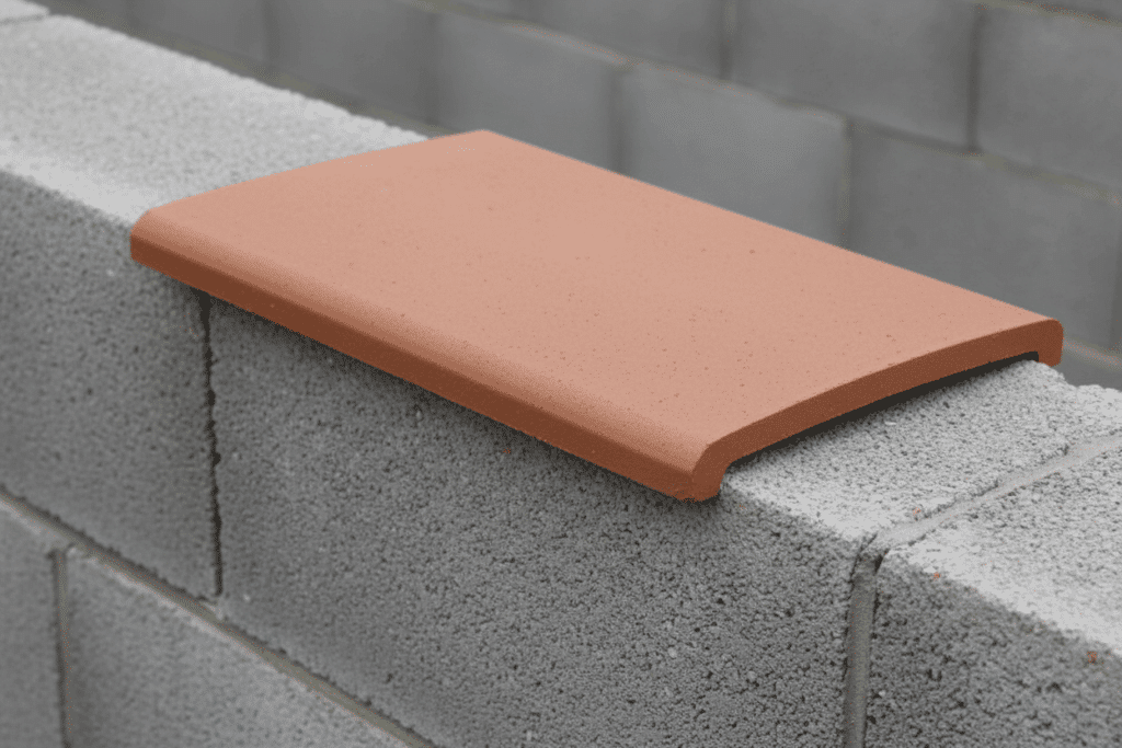 Albardilla cerámica instalada por Sabaya sobre un muro de obra, mostrando su diseño en forma de U y cómo actúa como cubremuros